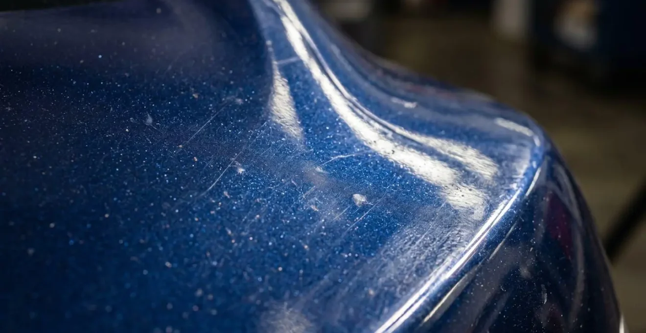 Inspection minutieuse de la carrosserie d'une voiture avec reflets révélant l'état de surface