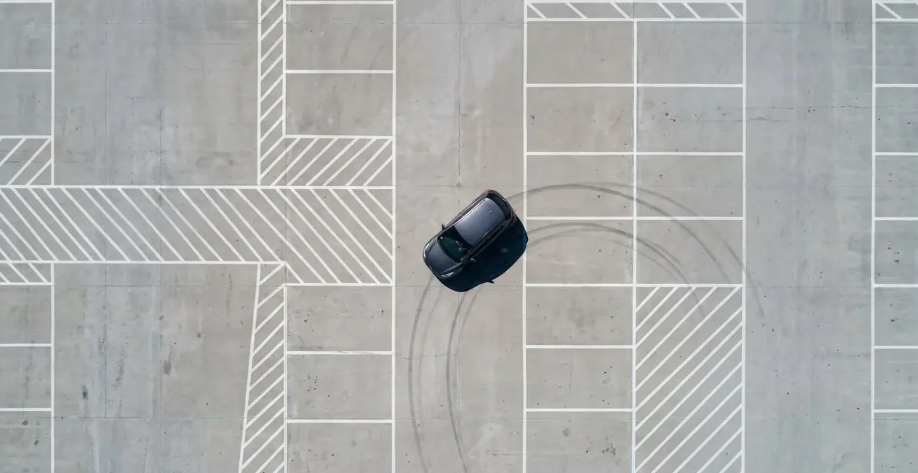 Vue aérienne minimaliste montrant trajectoire courbe d'une voiture reculant dans un parking